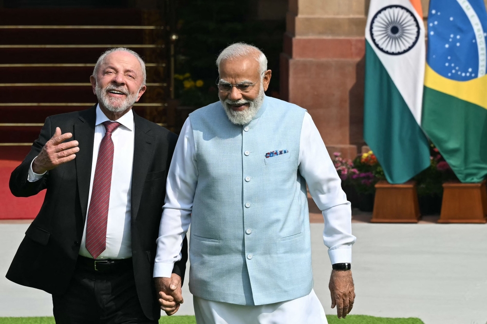 India's Prime Minister Narendra Modi (R) holds hands with Brazil's President Luiz Inacio Lula da Silva as they walk before their meeting at the Hyderabad House in New Delhi. — AFP pic