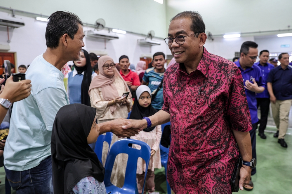 Datuk Seri Mohamed Khaled Nordin interacts with a member of the public at the Back-To-School programme for the Pasir Gudang parliamentary constituency. — Bernama pic