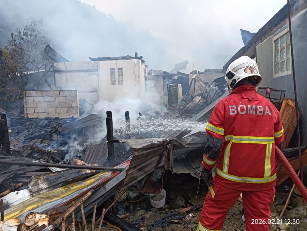 Smoke rises from the charred remains of homes in Kampung Melangkap Kapa as firefighters carry out final extinguishing and overhaul work. — Daily Express