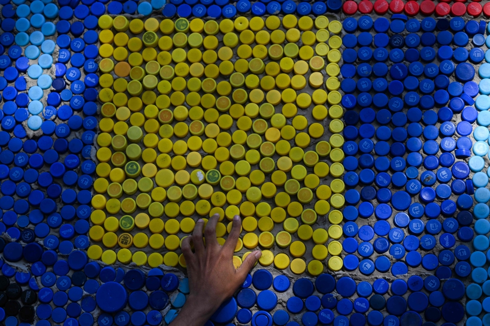 Venezuelan artist Oscar Olivares checks his mural made with plastic bottle caps on an apartment building in the Zacamil neighborhood in Mejicanos, El Salvador, on February 20, 2026. — AFP pic