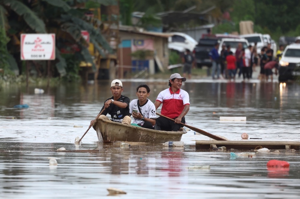 Some residents used boats to leave after the Paitan–Kanibongan road was cut off by floodwaters in Kampung Kubambangan during a survey today. — Bernama pic