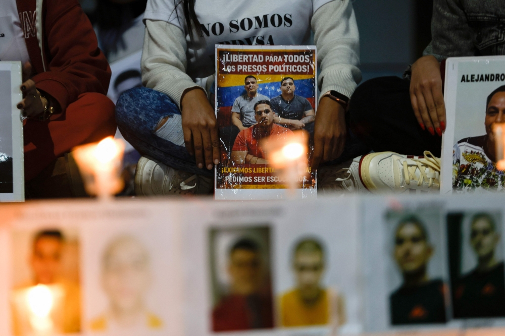 People show signs during a vigil to demand the freedom of political prisoners outside the El Helicoide building, headquarters of the Bolivarian National Intelligence Service (SEBIN), in Caracas. — AFP pic