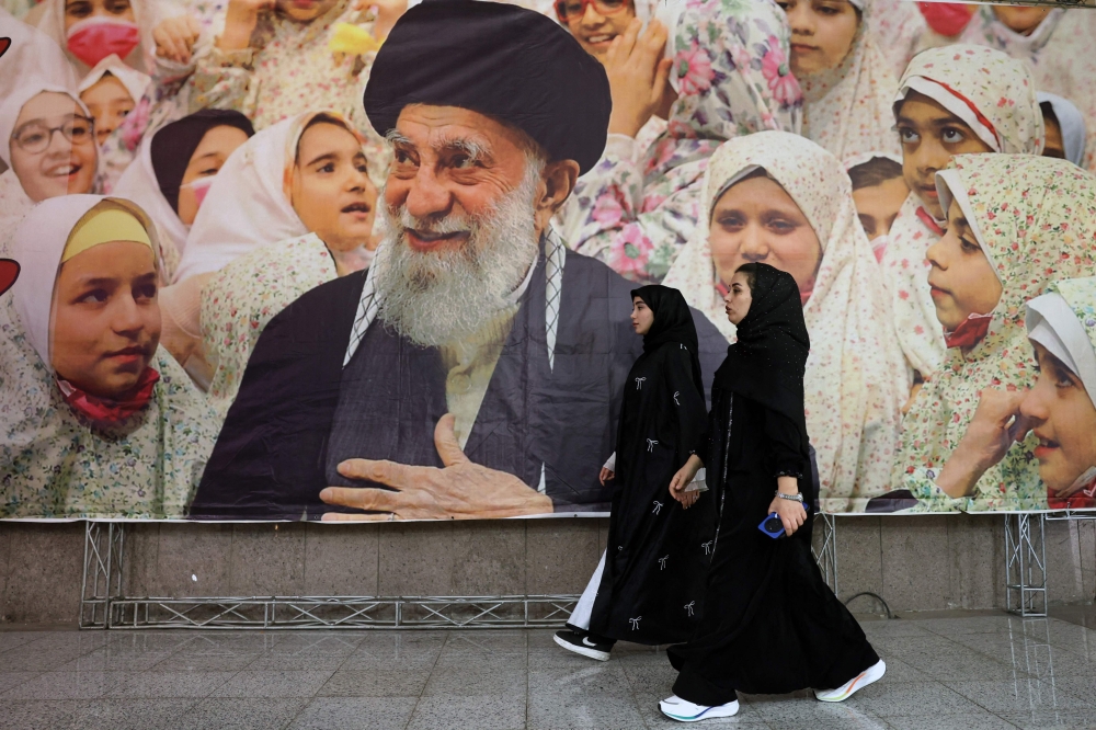 Iranian women walk past a banner bearing a portrait of Iran’s supreme leader Ayatollah Ali Khamenei at the Imam Khomeini Grand Mosque in Tehran February 22, 2026. — AFP pic