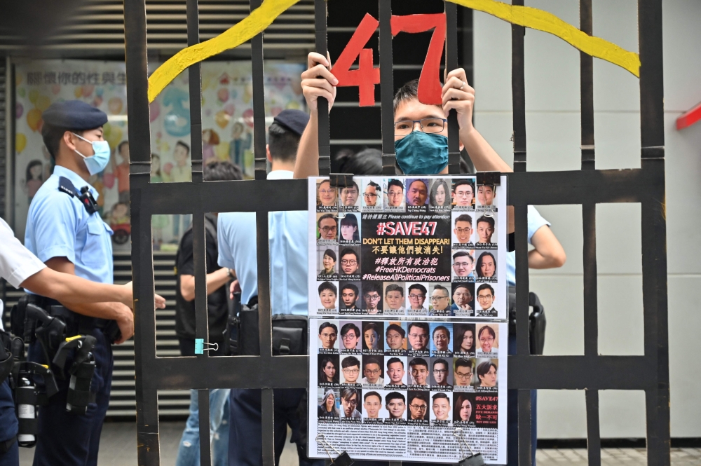 A protester stands behind a mock jail displaying with photos of the 47 detained pro-democracy figures. Hong Kong’s Court of Appeal today upheld the jailing of 12 activists in a major subversion case under Beijing’s national security law. — AFP pic