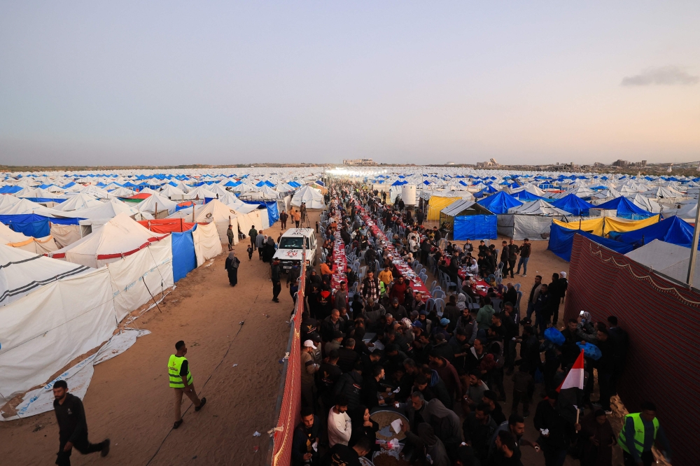 Displaced Palestinian families sit at communal long tables as they gather to break the dawn-to-dusk Ramadan fast during Iftar, in the al-Zahara neighbourhood, north of the Nuseirat refugee camp in the central of Gaza Strip on February 21, 2026. — AFP pic 