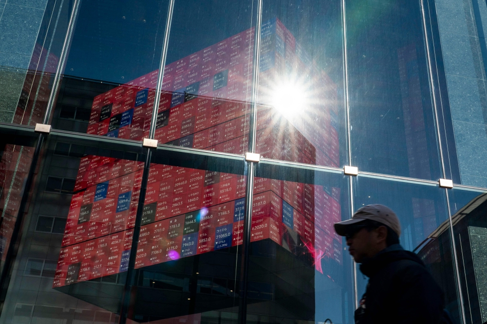 A man walks past an electronic quotation board displaying the Nikkei 225 stock prices on the Tokyo Stock Exchange in Tokyo. Seoul, the standout market this year thanks to a shift into chip giants such as Samsung and SK hynix, climbed more than one per cent to another record, while Tokyo also advanced as it reopened after a long weekend. — AFP pic