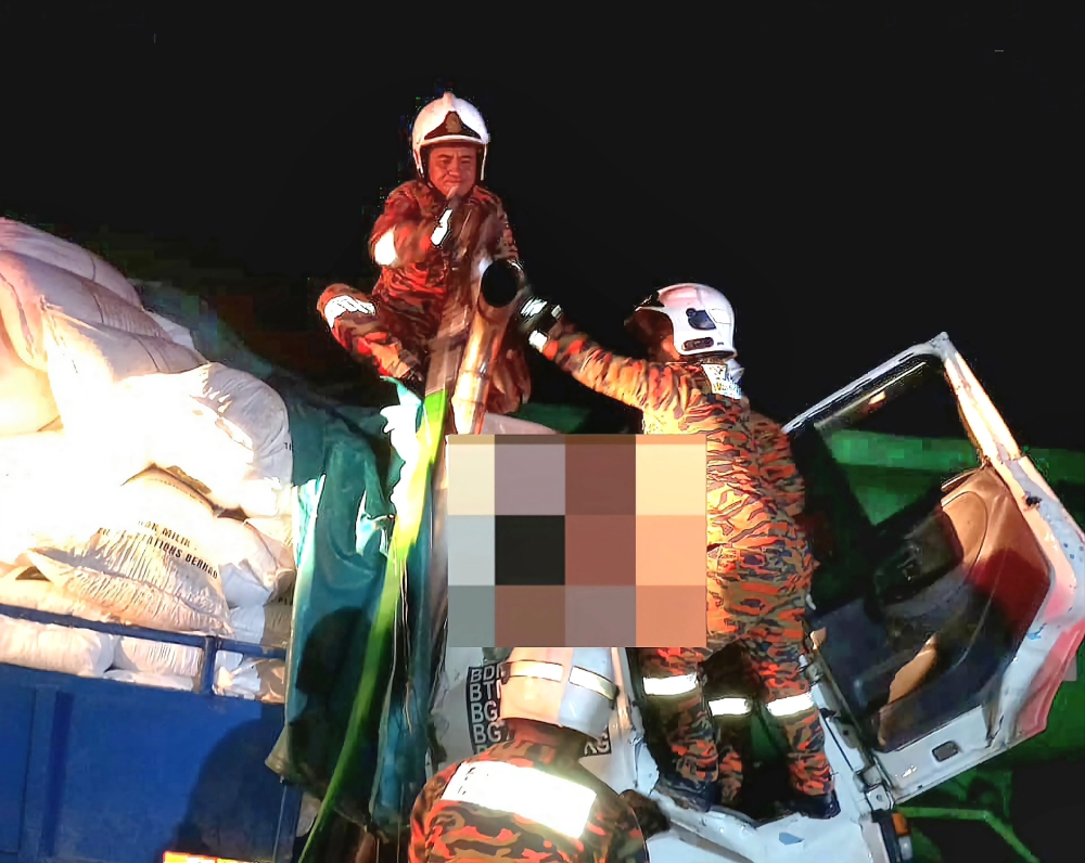 Firefighters work to extricate victims from the lorry that was carrying fertiliser. — Picture courtesy of Bomba via The Borneo Post