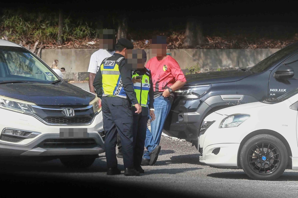 Road Transport Department (JPJ) personnel check a person believed to be a middleman or “Tonto” during Ops Middleman in Nilai, Negeri Sembilan on February 24, 2026. — Picture by Sayuti Zainudin