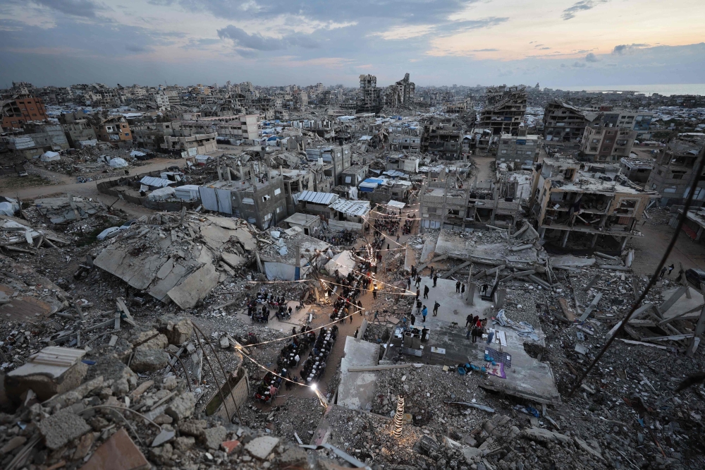 Displaced Palestinians gather for their fast-breaking Iftar meal amid the rubble of destroyed buildings at the Jabalia refugee camp in the northern Gaza Strip. — AFP pic