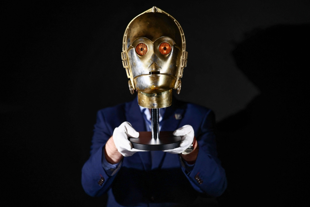 This photo taken on January 30, 2026 shows a gallery assistant posing with a ‘Light-Up C-3PO Head’ from the 1980 movie ‘Star Wars: The Empire Strikes Back’, at a preview by memorabilia auction house Propstore in Rickmansworth, near London. A collection of around 1,550 pieces of film and TV history will go under the hammer over three days from March 25, with in-room bidding on the first day only at the Petersen Automotive Museum in Los Angeles. — AFP pic 