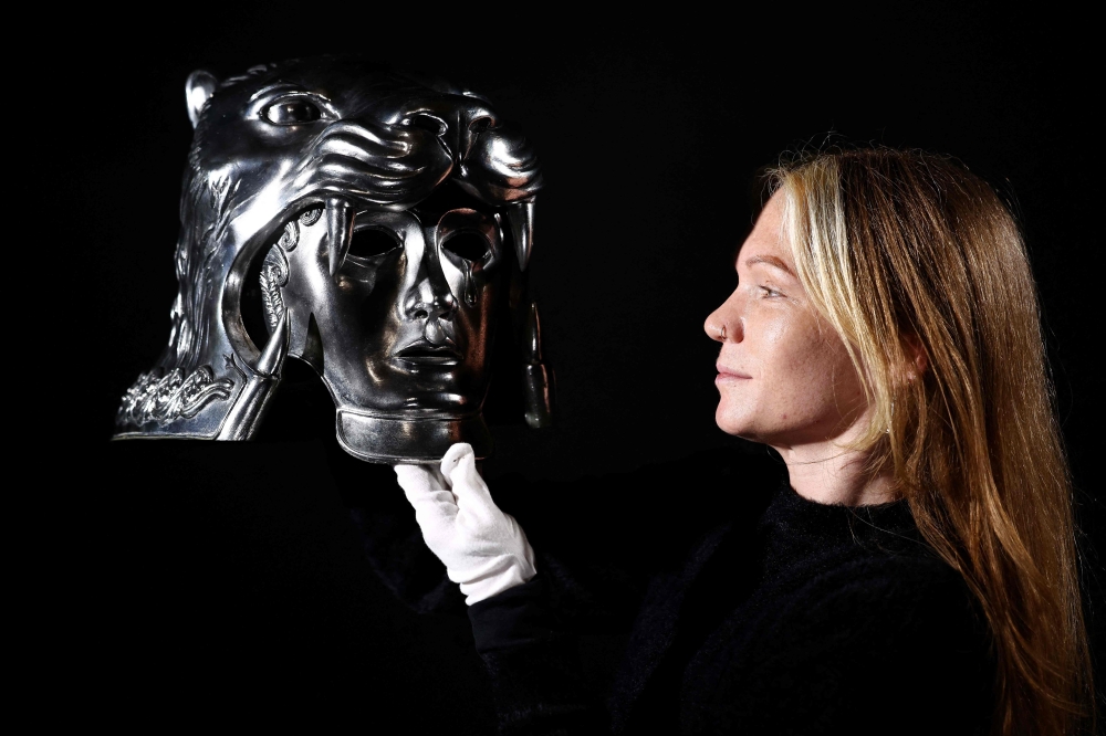 This photo taken on January 30, 2026 shows a gallery assistant posing with the ‘Production-Made Tigris of Gaul Helmet’ from the 2000 movie ‘Gladiator’, at a preview by memorabilia auction house Propstore in Rickmansworth, near London. — AFP pic 