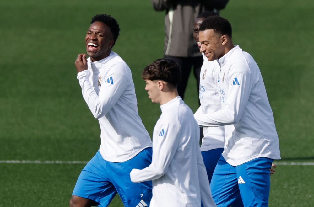 Real Madrid’s Brazilian forward #07 Vinicius Junior, Real Madrid’s French forward #10 Kylian Mbappe (right) and teammates smile during a training session on the eve of their Uefa Champions League knockout round play-off second leg football match against SL Benfica at Real Madrid Sports City in Valdebebas, in the outskirts of Madrid on February 24, 2026. — AFP