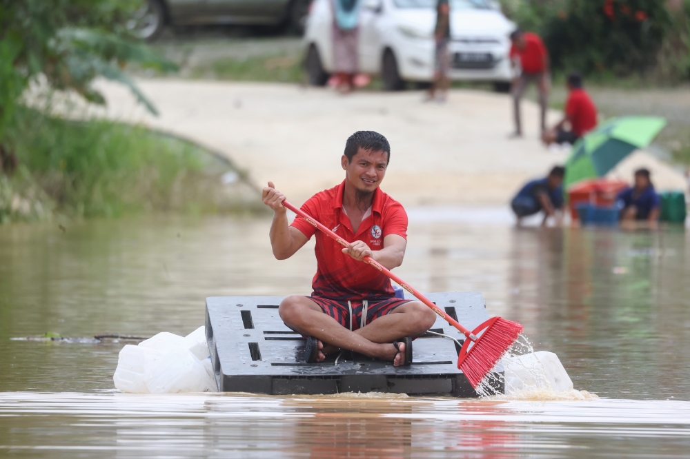 Floods in Paitan forced a resident to use a makeshift raft to obtain necessities on February 21, 2026. — Bernama pic
