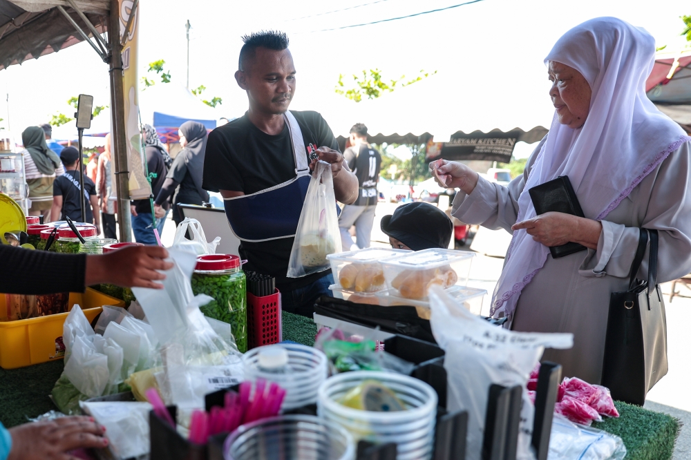 Mersing Cendol Padu vendor, Zulhairie Muda (left) serves a customer at the Rahmah Ramadan Bazaar in Taman Wawasan, Mersing February 26, 2026. — Bernama pic