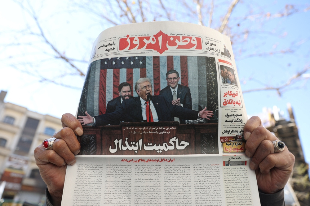 A man shows a newspaper with a front-page photo depicting US President Donald Trump delivering the State of the Union address, in Tehran February 26, 2026. — Majid Asgaripour/Wana (West Asia News Agency) pic via Reuters