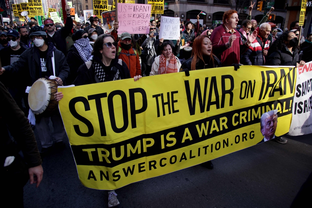People hold signs and a banner during the “Stop the War on Iran” protest at Times Square in New York City on February 28, 2026. — AFP pic