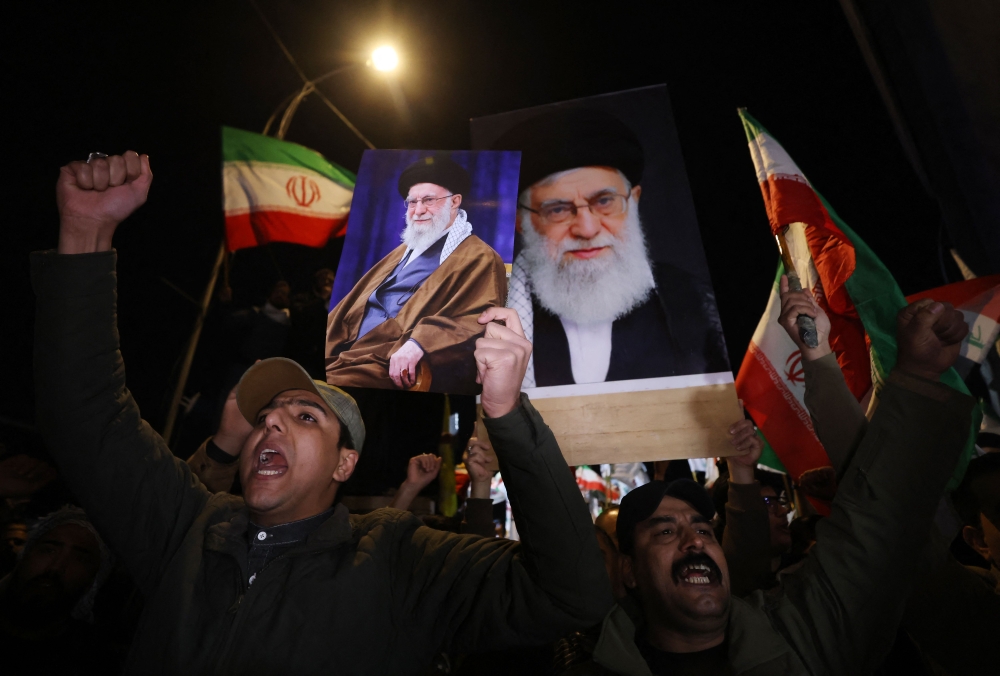 Iraqi Shiites shout slogans as they carry a portrait of Iran’s Supreme Leader Ayatollah Ali Khamenei and wave Iran flags during a protest against US and Israeli attacks on Iran at a bridge leading to the Green Zone in Baghdad on February 28, 2026. — AFP pic