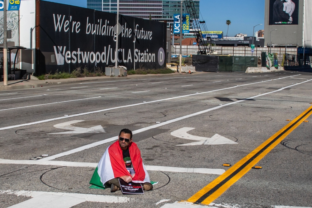 A man wrapped in an Iranian pre-1979 Islamic Revolution flag sits in the middle of the road while members of the Iranian community celebrate in Los Angeles, on February 28, 2026, the same day the US and Israel launched an attack of unprecedented scale against Iran, reportedly killing more than 200 people, with Tehran launching a retaliatory missile barrage that sent people running for cover across the Middle East. — AFP pic