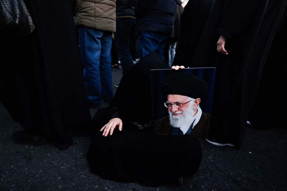 The assassination of Iran’s supreme leader marks a dangerous new phase — Phar Kim BengMARCH 1 — Iran has now officially confirmed what many feared in the first hours of the air strikes: its Supreme Leader, Ali Khamenei, has been killed.This admission by Tehran transforms speculation into strategic reality.What began as a wave of joint US–Israeli strikes has now escalated into the decapitation of the highest authority in the Islamic Republic. The death of Khamenei is not merely the elimination of a head of state.It is the removal of the ultimate religious, political and military arbiter in a system uniquely structured around clerical supremacy. The Middle East has entered a far more dangerous chapter.For decades, Khamenei stood at the apex of Iran’s hybrid structure – balancing republican institutions, clerical authority and the vast influence of the Islamic Revolutionary Guard Corps.He was not a ceremonial figure. He was the final word on war, peace, nuclear policy and regional strategy. His death creates both a vacuum and a crucible.Under Iran’s constitution, the Assembly of Experts will appoint a successor.But constitutional procedure alone cannot guarantee stability in a moment like this.The real question is whether the transition will be orderly – or shaped by the hard power calculations of the IRGC.The paradox of negotiation and forceThere is a profound paradox here. Khamenei, despite his ideological rigidity, had at various junctures endorsed negotiations – even indirect engagement – with Western powers.Yet he was killed during a moment of heightened confrontation. The message this sends to any successor is stark: negotiation does not necessarily shield a leader from force.That alters incentives. Any incoming Supreme Leader will have to consolidate authority swiftly.But legitimacy in revolutionary Iran is rarely secured through compromise. It is secured through resistance.The successor will need to demonstrate not only theological credentials, but strategic resolve – particularly in coordination with the IRGC.If the new leader appears conciliatory, he risks alienating the security establishment and a population likely to rally around nationalist sentiment in the face of external attack.History shows that leadership decapitation does not automatically weaken a state. It can radicalise it.When a political system is fused with religious legitimacy, the assassination of its supreme authority can transform geopolitical rivalry into existential narrative. The conflict ceases to be about centrifuges or missile ranges.It becomes framed as survival of sovereignty and faith.That framing is combustible.Regional and global implicationsRegionally, Gulf states now face heightened uncertainty. Missile exchanges may intensify.Proxy theatres in Lebanon, Syria, Iraq and Yemen may heat up.Shipping lanes through the Strait of Hormuz could become vulnerable to disruption. Insurance premiums will spike. Energy markets will react.For Malaysia and Asean, this is not a distant war. Malaysia is a trading nation deeply embedded in global supply chains. Energy price volatility will affect inflation and fiscal planning.Thousands of Malaysians work across the Gulf. Contingency evacuation planning is not alarmism; it is prudence.More broadly, Asean must maintain its longstanding principle of neutrality while urging de-escalation.The region cannot afford a prolonged Middle Eastern conflagration layered atop existing global tensions.The United States and Israel may calculate that removing the Supreme Leader disrupts command and control. But disruption does not equal capitulation.It can produce fragmentation – and fragmentation can produce escalation.The greater risk now lies in miscalculation.If Iran’s next leader feels compelled to establish military credibility rapidly, retaliatory strikes may intensify.If the IRGC assumes a more overt role in national decision-making, the balance between clerical and military authority may shift in ways that harden strategic posture.In such circumstances, diplomacy becomes harder precisely when it is most necessary.Longer-term considerationsThere is also a longer-term question.If supreme leaders can be targeted and eliminated, what precedent does that set for international norms?Assassination at the apex of sovereign leadership erodes already fragile constraints in global politics.Once such thresholds are crossed, they are difficult to restore.Iran’s official confirmation of Khamenei’s death closes the door on ambiguity. It opens the door to unpredictability.The immediate priority for governments worldwide must be the protection of citizens and economic resilience.The strategic priority must be preventing a leadership vacuum from spiralling into generational war.The Middle East has witnessed regime change before. It has endured invasion, sanctions and proxy conflict.Yet the assassination of a sitting Supreme Leader marks an escalation of a different order.The world must now hope that cooler calculations prevail in Tehran, Washington and Tel Aviv.Because once wars become battles of legitimacy and survival, they rarely end quickly – and they rarely end cleanly.*Phar Kim Beng is professor of Asean Studies and director of the Institute of International and Asean Studies, International Islamic University of Malaysia. ** This is the personal opinion of the writer or publication and does not necessarily represent the views of Malay Mail.A woman holds a poster of Iran’s supreme leader Ayatollah Ali Khamenei, who was killed in joint US and Israeli strikes, as mourners gather at a square in Tehran, Iran on March 1, 2026. — AFP pic