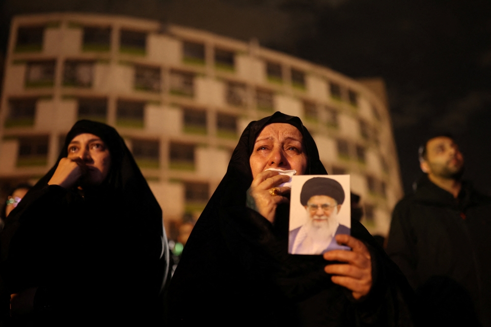 A woman holds on to a picture of Iran's Supreme Leader Ayatollah Ali Khamenei at the Vali-Asr Square, after he was killed in Israeli and U.S. strikes on Saturday, in Tehran March 1, 2026. — Majid Asgaripour/Wana (West Asia News Agency) pic via Reuters