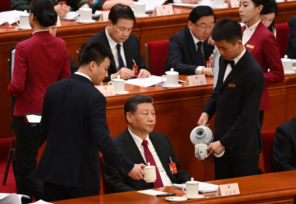 Workers replenish Chinese President Xi Jinping’s teacups during the opening session of the National People’s Congress at the Great Hall of the People in Beijing on March 5, 2024. — AFP pic