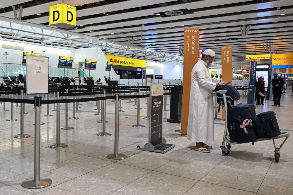 A man stands in front of a closed check-in counter for Gulf carrier Etihad at London Heathrow Airport on March 1, 2026, as flights are severely disrupted following the US and Israel’s strikes on Iran. — AFP pic