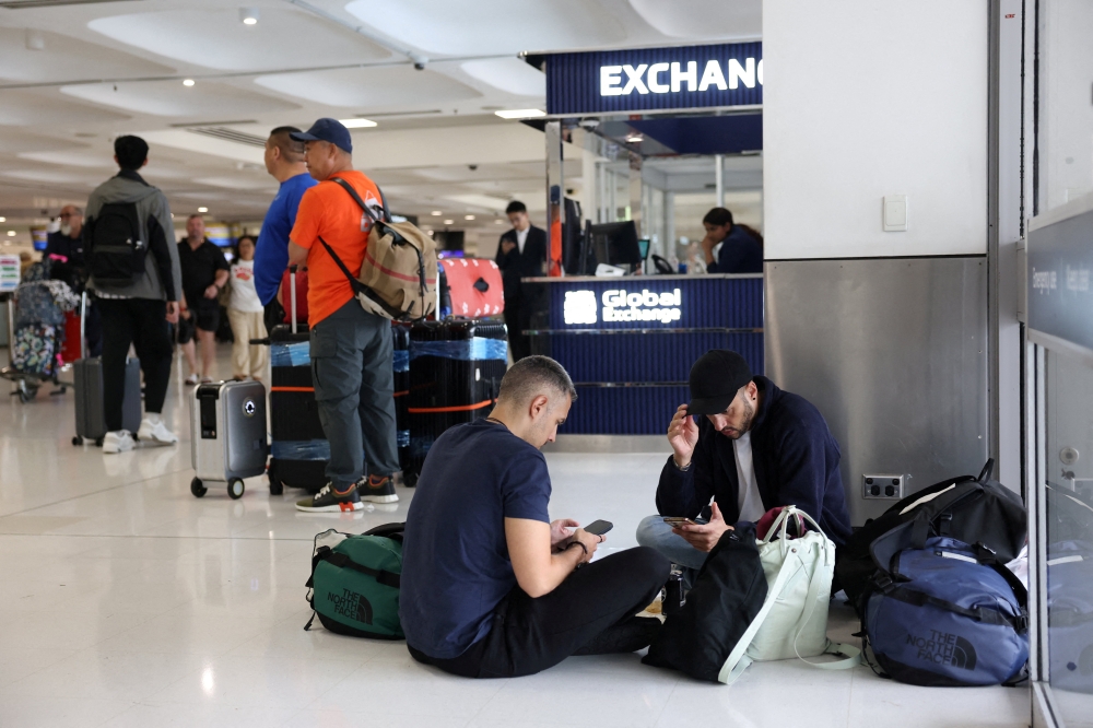 Stranded travellers sit on the floor at Sydney Airport after their standby flight to Switzerland via Doha was cancelled, in Sydney March 2, 2026. — Reuters pic 