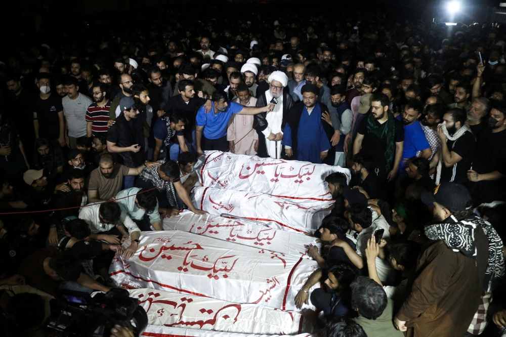 People gather beside coffins of victims, who were killed after they breached an outer wall of the US Consulate General during a protest following news of US and Israeli strikes on Iran that killed late Iran’s Supreme Leader Ayatollah Ali Khamenei, during their funeral in Karachi March 1, 2026. — Reuters pic  
