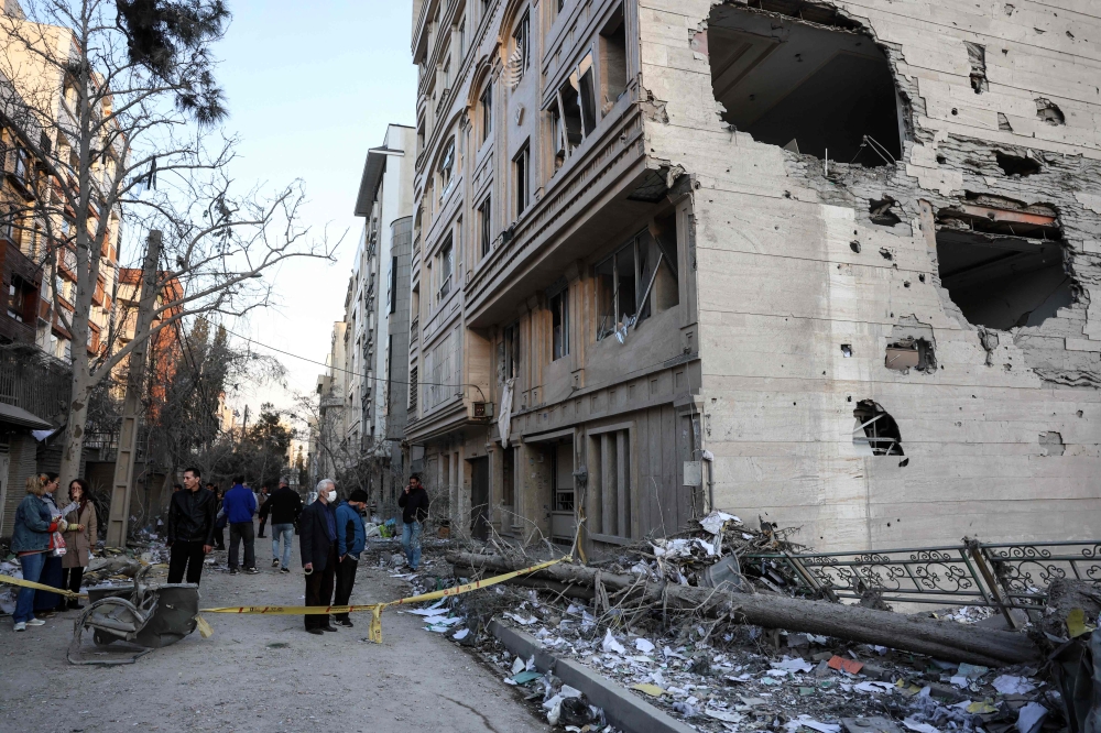 Residents stand on a street beside damaged residential buildings near Niloufar square in Tehran during the ongoing joint US-Israeli military campaign on Iran on March 2, 2026. — AFP pic