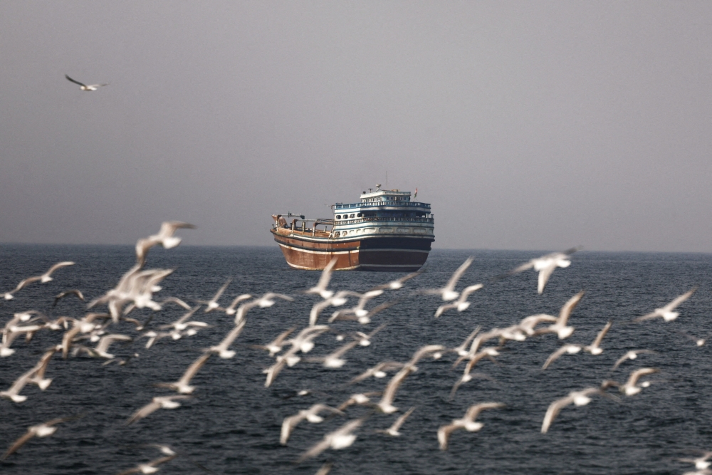Birds fly near a boat in the Strait of Hormuz, as seen from Musandam, Oman. A senior Iranian Revolutionary Guards official said the strait is closed and that forces will fire on any ship attempting to pass. — Reuters pic