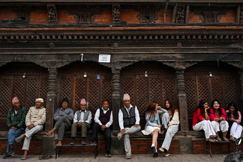 People sit at Patan Durbar Square in Lalitpur on March 2, 2026, ahead of the general elections in Nepal. — AFP pic