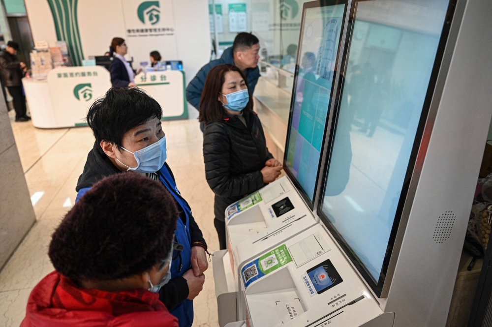 Yan Sulian (second left) helps a patient with electronic registration at a community health centre in Shanghai on February 11, 2026. — AFP pic