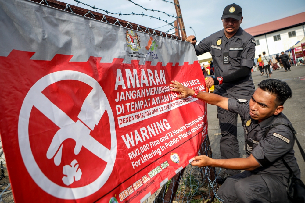 This file picture shows SWCorp Perlis enforcement officers hanging a banner warning against littering at Arau Ramadan Bazaar, Arau, February 26, 2026. — Bernama pic