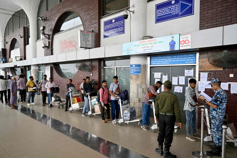 A security personnel checks documents of passengers at the Hazrat Shahjalal International Airport in Dhaka on March 3, 2026 as airlines cancelled flights amid the Middle East conflict. Governments and airlines scrambled yesterday to repatriate tens of thousands of travellers stranded in the Middle East following the eruption of a regional conflict sparked by Israel-US strikes on Iran. — AFP pic 