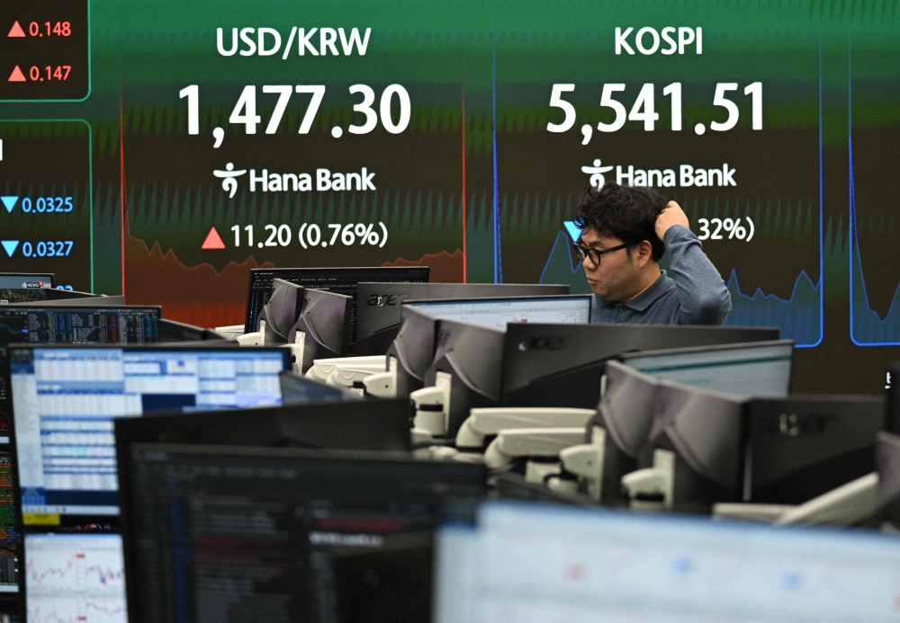 A currency dealer monitors exchange rates as an electronic screen shows South Korea's benchmark stock index (Kospi) and the Korean won/USD exchange rate (left) in a foreign exchange dealing room at the Hana Bank headquarters in Seoul on March 4, 2026. — AFP pic 