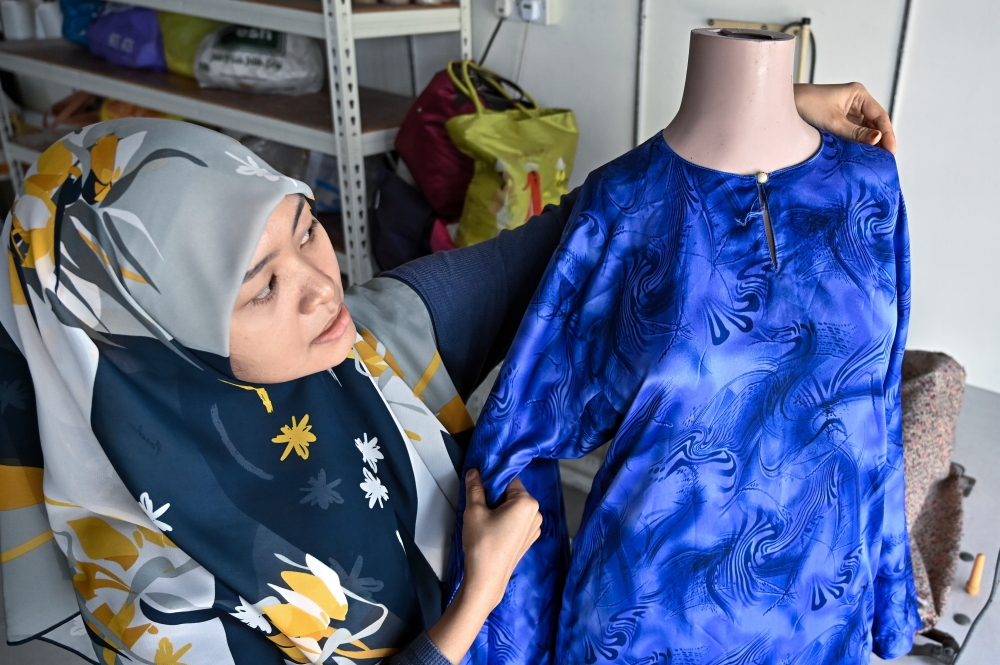 Tailor Siti Aishah Norazhar at Kedai Jahit Aishah in Ipoh, where she now focuses more on clothing alterations as customers increasingly bring in ready-made and online-purchased Raya outfits for adjustments. — Bernama photo