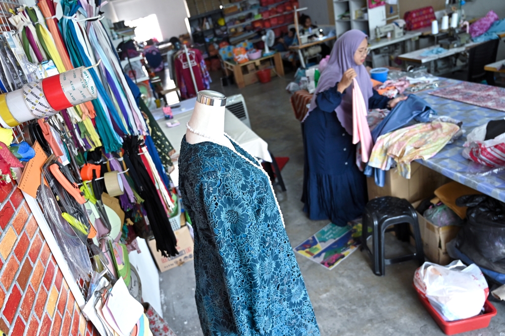 Helmaliza Md Isa works on a garment at her tailoring shop in Ipoh, where demand for clothing alterations has surged as more customers bring in Raya outfits bought online to ensure the perfect fit. — Bernama photo