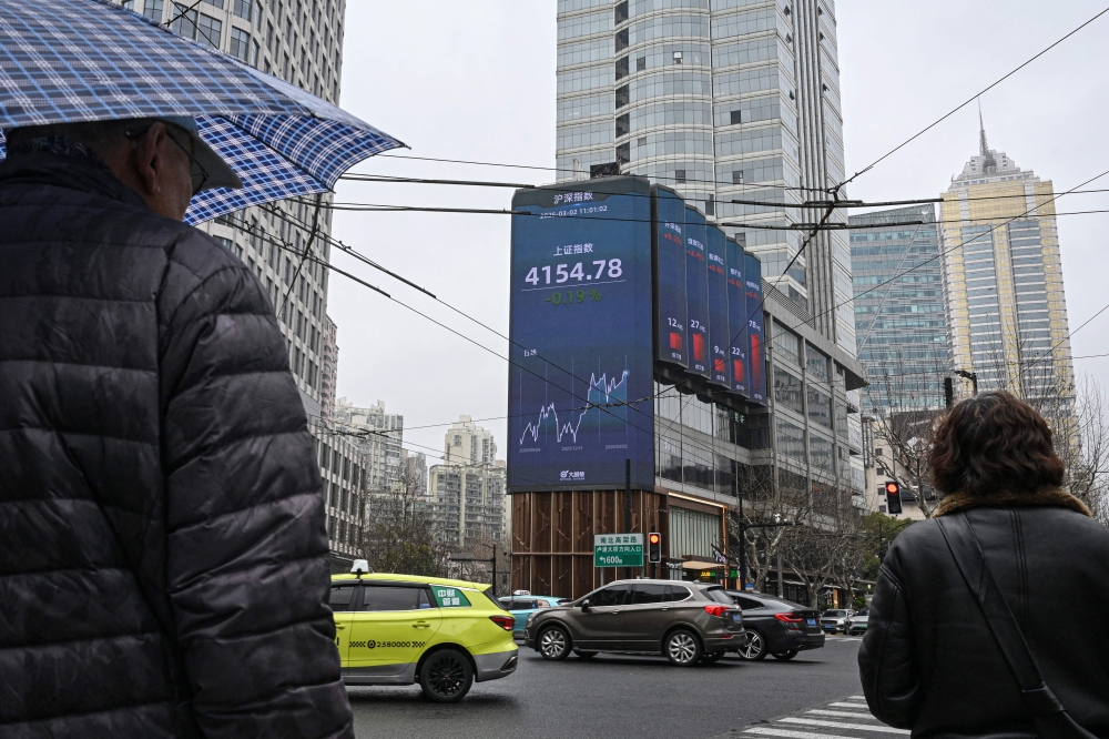 Pedestrians walk past a screen showing the Shanghai composite index in the Jing’an district of Shanghai on March 2, 2026. — AFP pic 