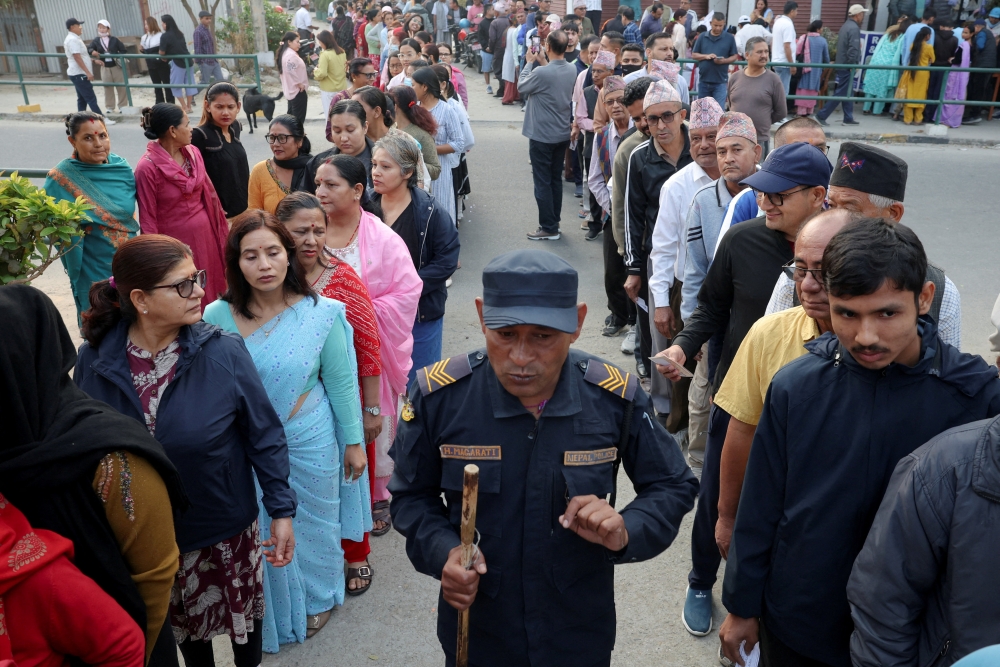 People stand in queues to vote outside a polling station, as a policeman walks by during the general election in Damak, Jhapa district, Nepal, March 5, 2026. — Reuters pic 