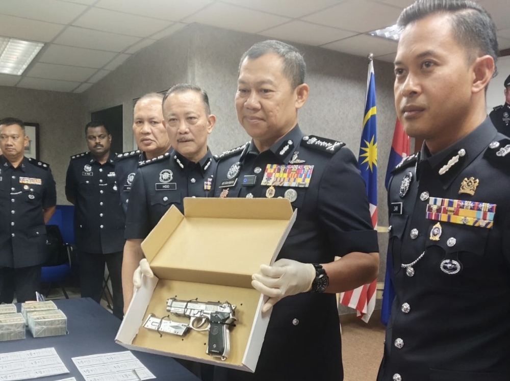 Johor police chief Datuk Ab Rahaman Arsad holds up the imitation firearm used in a robbery during a press conference at the Johor police contingent headquarters in Johor Bahru, March 5, 2026. — Picture by Ben Tan