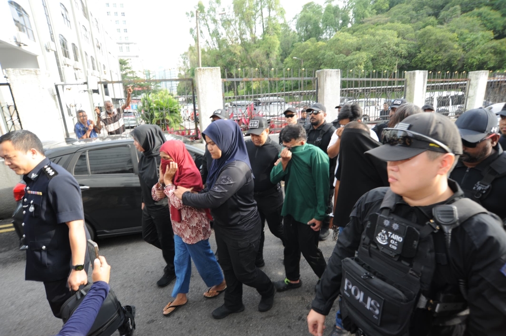 Six individuals allegedly involved in a RM500,000 gang robbery are escorted into the Johor Bahru court complex under armed police guard. — Picture by Ben Tan