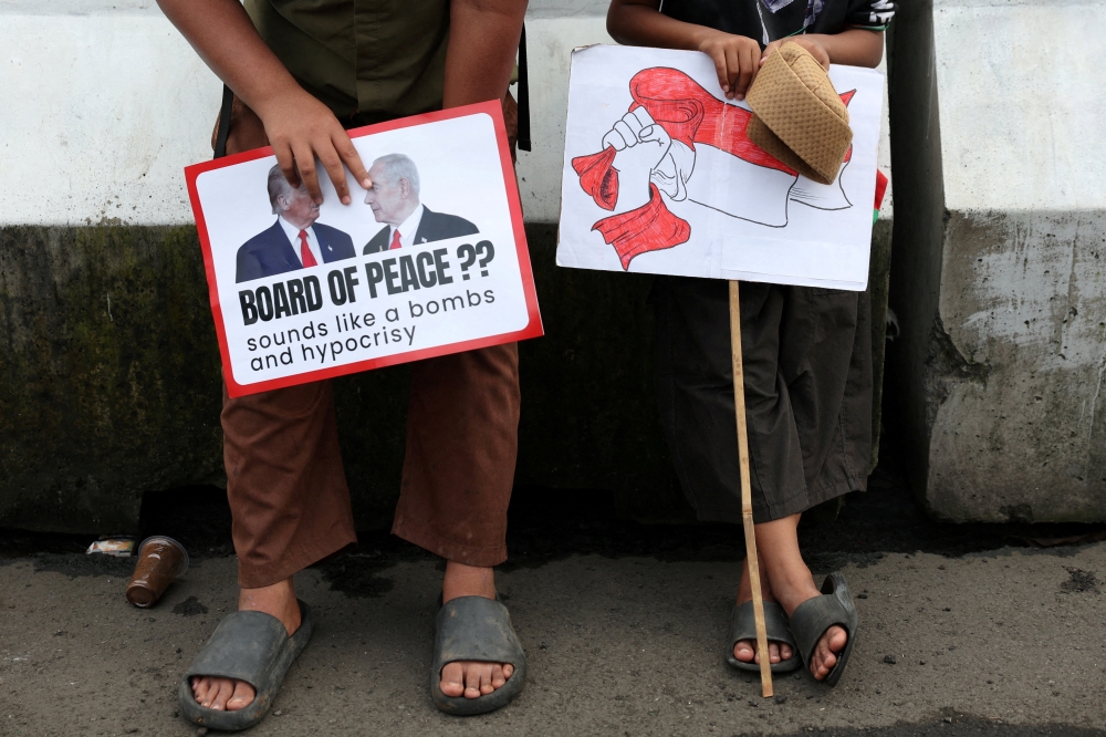 Boys in solidarity with Palestinians hold signs as they take part in a protest, outside the US embassy, against Israel and demanding that the Indonesian government cancel the proposed multinational peacekeeping force for Gaza, following  Indonesia’s President Prabowo Subianto invitation to Washington later this month for the first meeting of US President Donald Trump’s Board of Peace, in Jakarta February 13, 2026. — Reuters pic 