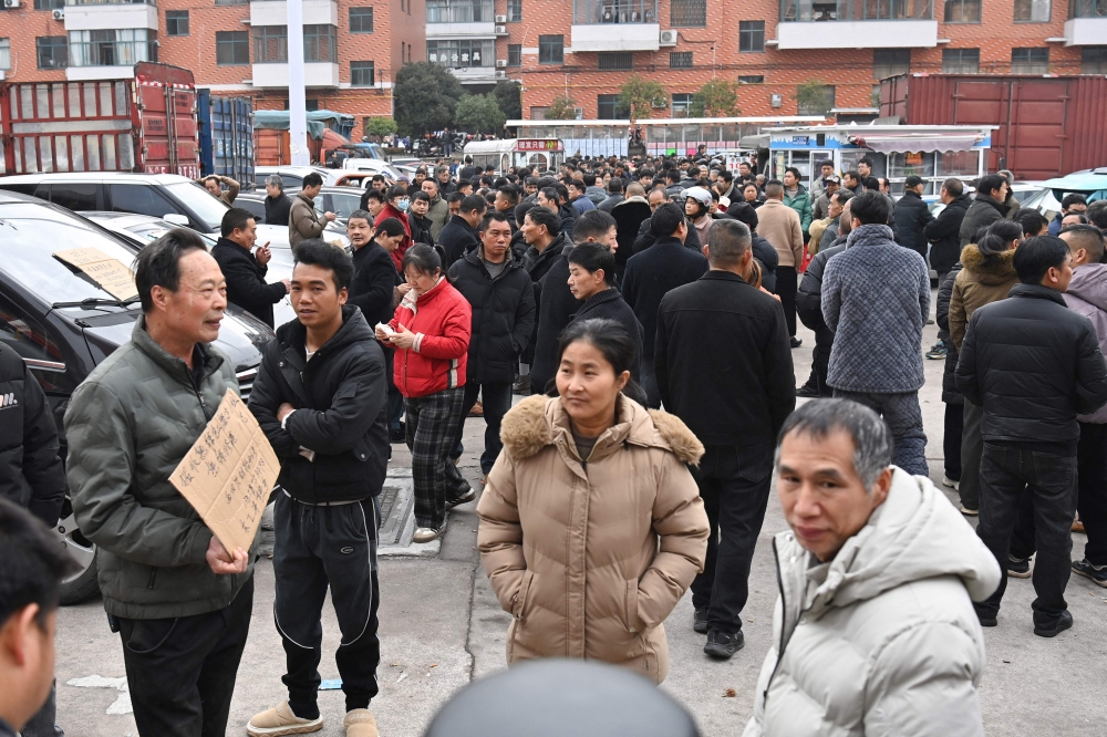 A recruiter (left) holds a notice detailing jobs on offer at a job fair in Dongyang, in China’s eastern Zhejiang province on March 6, 2026. — CN-STR/AFP pic 