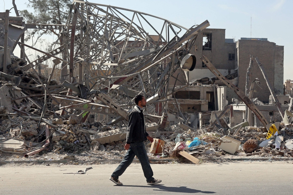 A man walks past destroyed buildings following airstrikes in central Tehran. The author argues that neither the US and Israel’s strikes on Iran nor any attempt by Iran to close the Strait of Hormuz can be justified under international law, as both actions fall outside the strict legal thresholds governing self-defence and freedom of navigation. — AFP pic