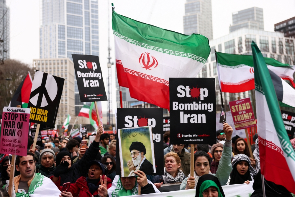 Anti-war activists hold signs, an image of Iran's late Supreme Leader Ayatollah Ali Khamenei, and Iranian flags as they gather outside the US embassy during a march in London, Britain on March 7, 2026. — Reuters pic