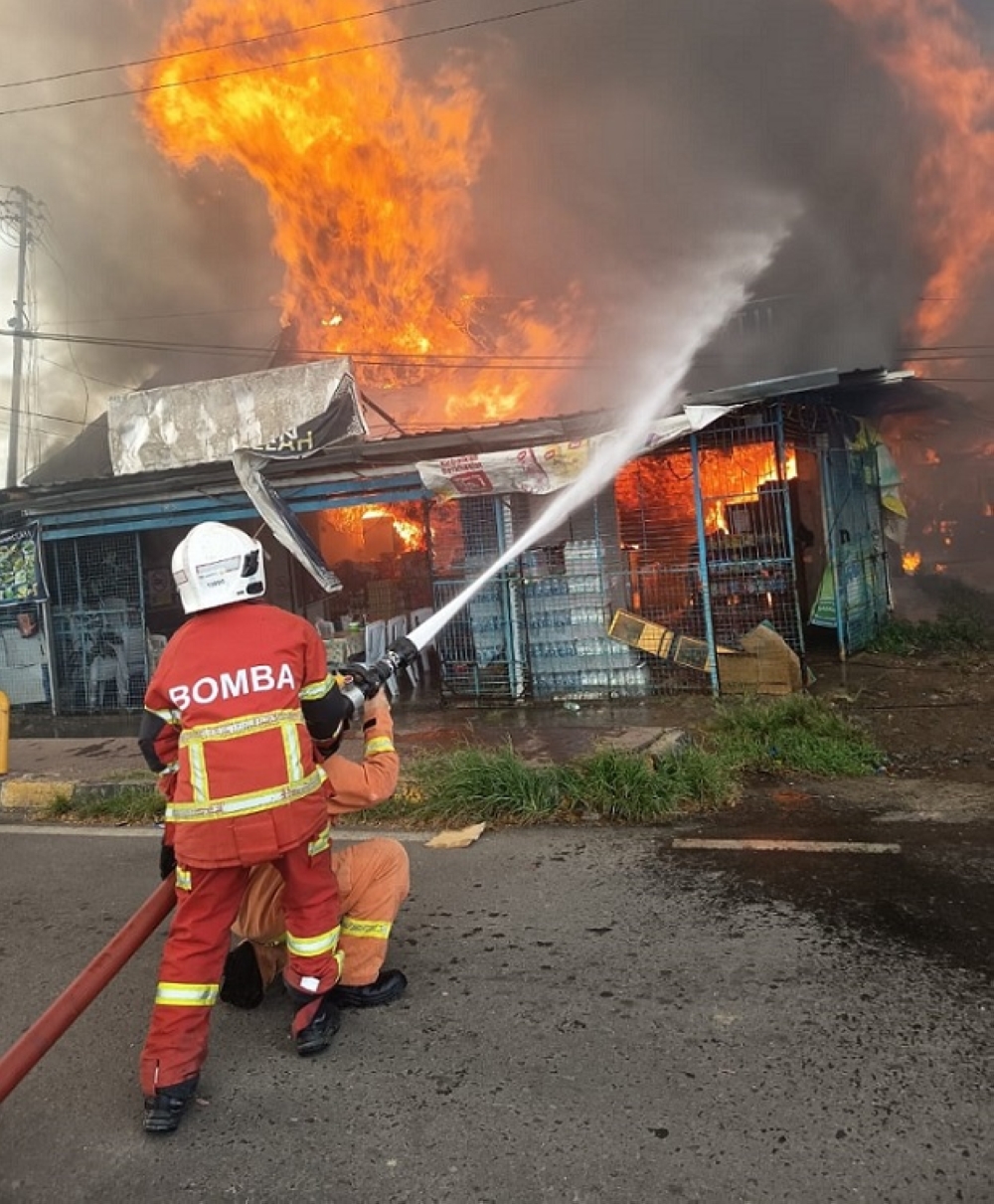Firefighters battle a blaze that destroyed several houses and shops in Kampung Air, Semporna. — Daily Express pic