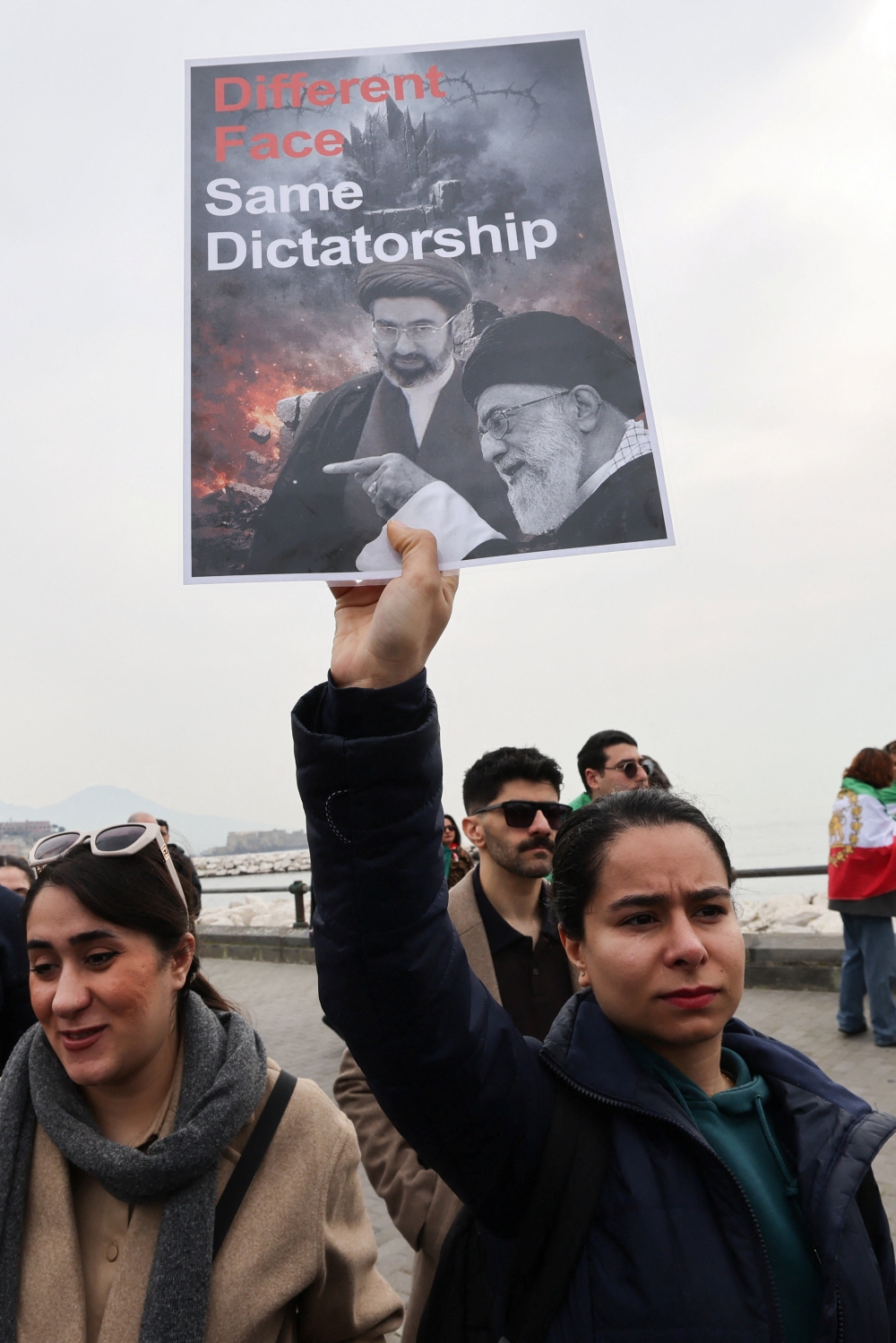A woman holds a banner against Iran’s late Supreme Leader Ayatollah Ali Khamenei and his son Mojtaba Khamenei during a protest in Naples, Italy on March 6, 2026. — Reuters pic
