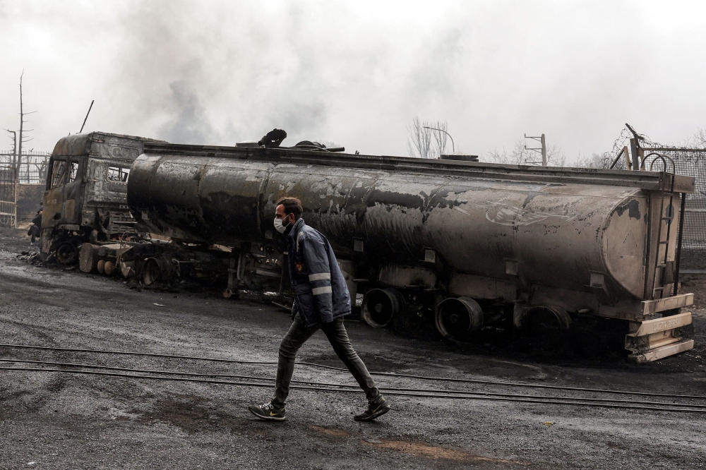An Iranian civil defence member walks next to a destroyed fuel tanker vehicle near an ongoing fire following an overnight airstrike on the Shahran oil refinery in northwestern Tehran on March 8, 2026. — AFP pic