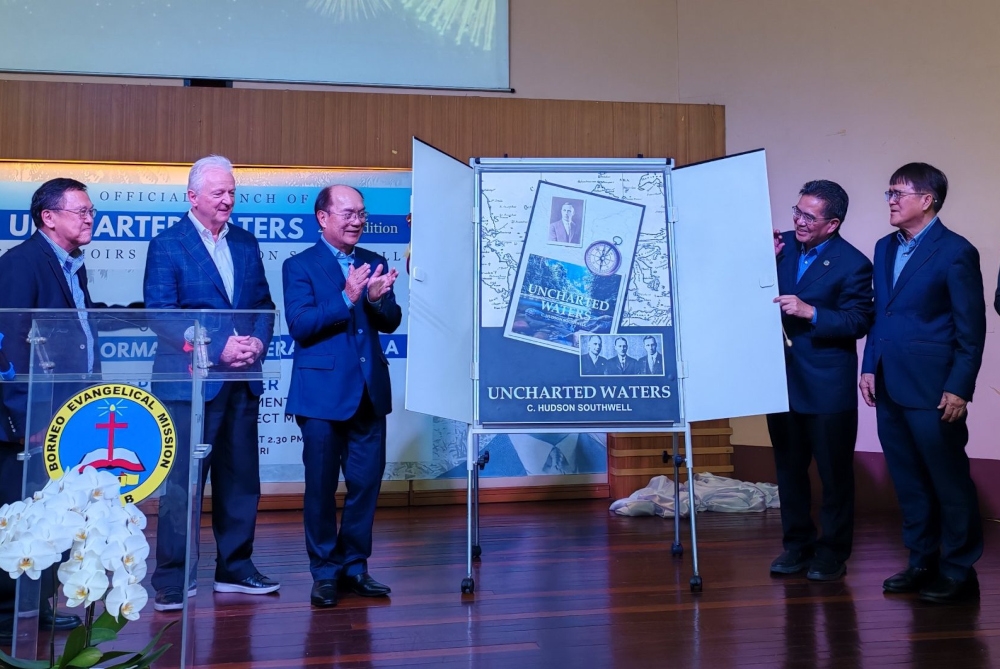 Datuk Gerawat Gala (third left) reacts after unveiling the book cover. From second left are Blair and Stanley Sigar. — The Borneo Post pic 