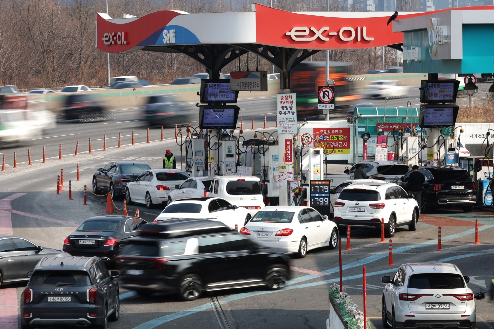 A board shows oil prices as cars wait in a line at a gas station in Seoul, South Korea on March 9. — Reuters pic